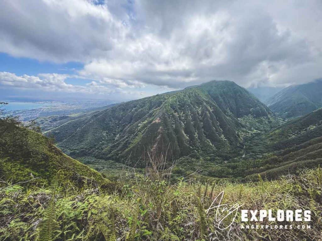Lush green mountains with dramatic cloud cover over a scenic landscape in Hawaii.